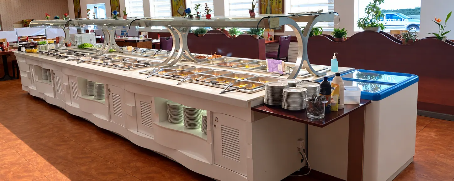 The long white buffet counter at Sushi d'or under yellow lanterns, with its stainless-steel displays.