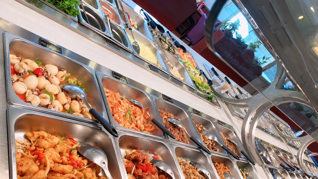 Row of buffet trays with their labels, spicy fish in the foreground.