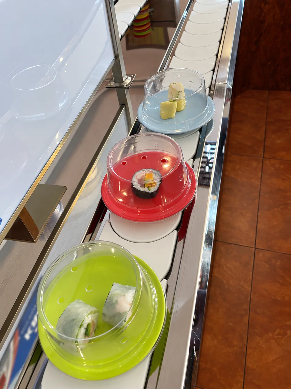 Three small plates under coloured domes (green, red, blue) on the conveyor belt.