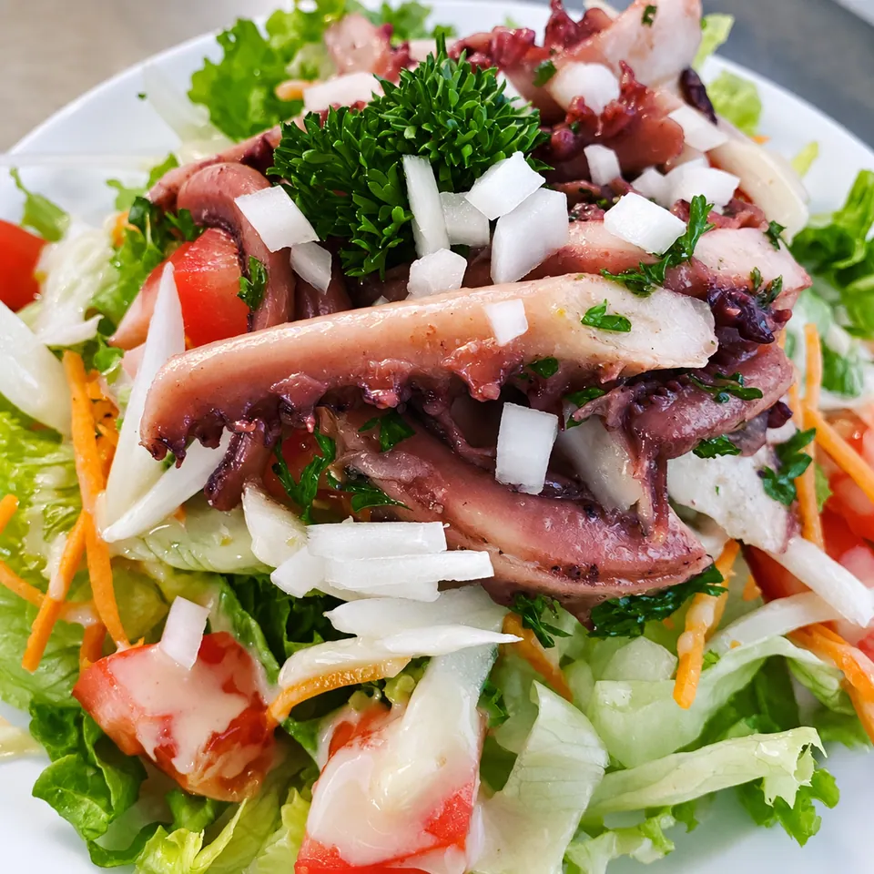 Octopus salad with tomatoes, onions and parsley.