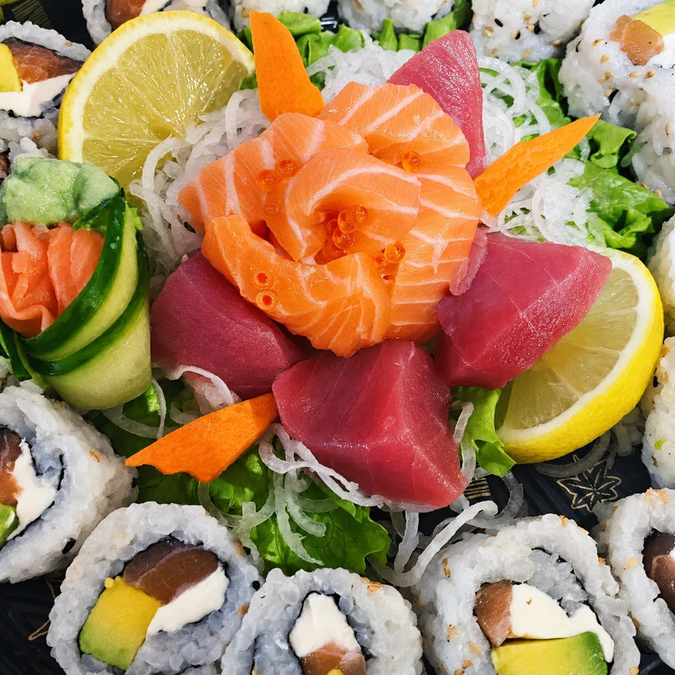 Sashimi platter: salmon rose, tuna, lemon, california rolls.